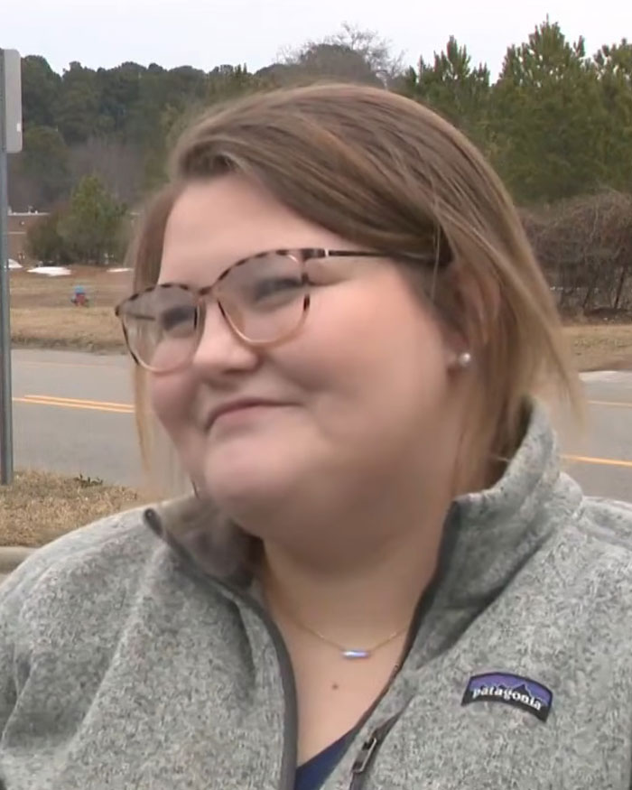 Vet tech wearing glasses and gray Patagonia jacket, speaking outdoors about rescuing abandoned dog during snowstorm.